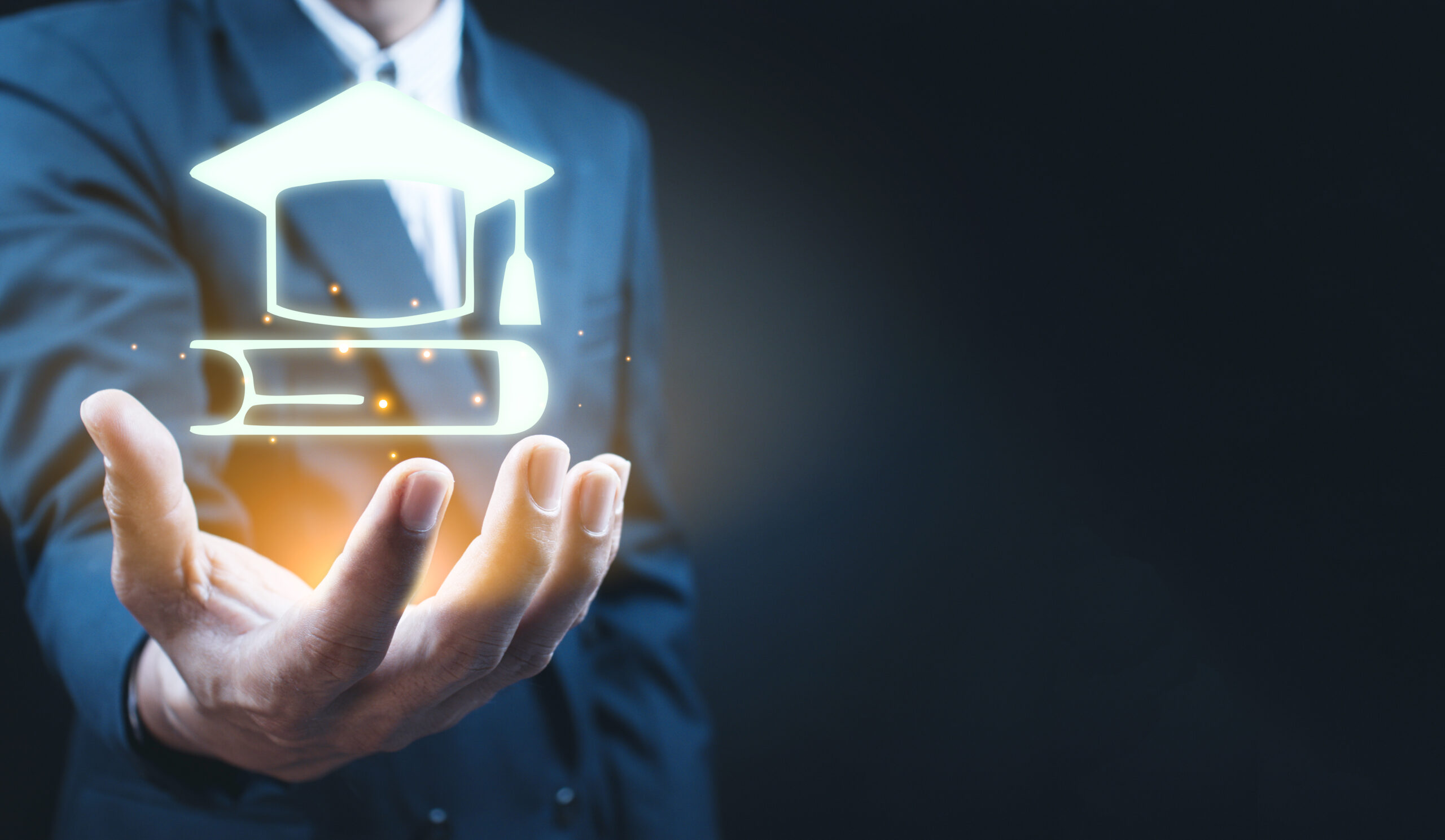 Businessman on dark background holding education success icon.
